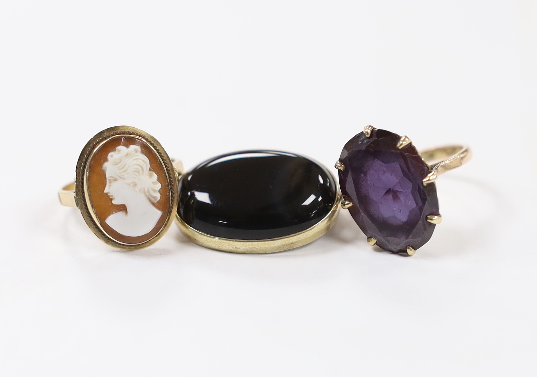 A 14k and oval cameo shell set ring, a 14k and synthetic colour change corundum set ring and a yellow metal and black onyx set brooch.